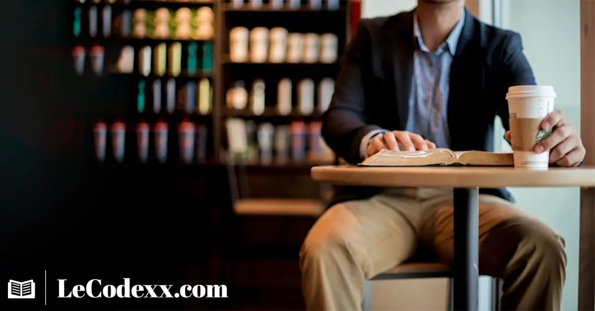 un homme entrain de lire en buvant un café dans une bibliotechque